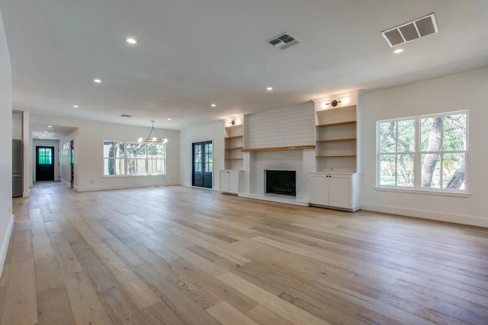 Open living room with shiplap fireplace, built-in shelving and hardwood floors