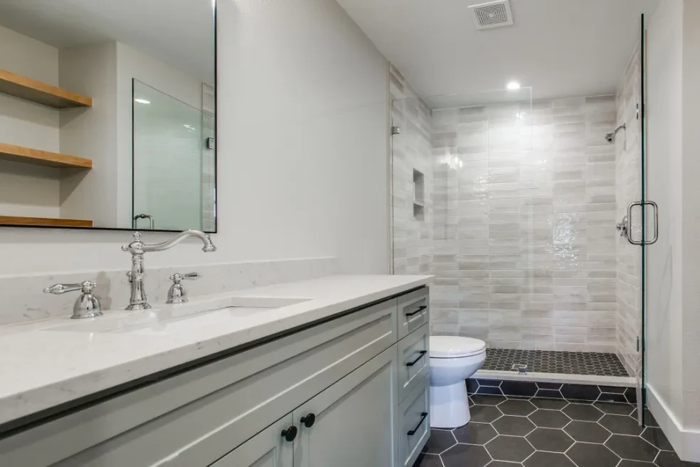 Secondary bath with gray vanity, marble countertop and hexagon tile shower