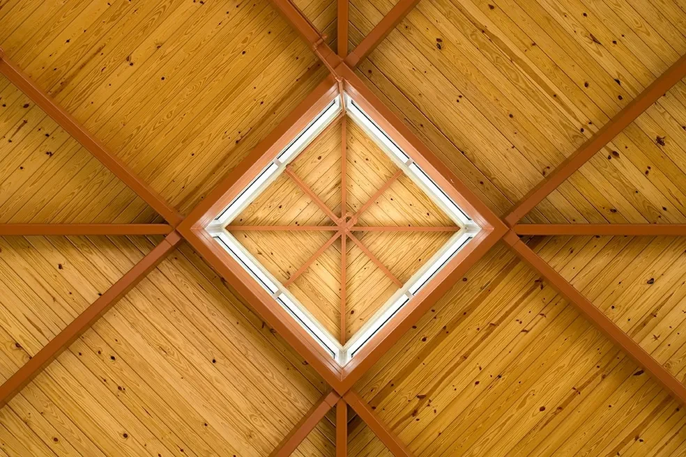 Geometric wood ceiling with diamond skylight and terracotta beams