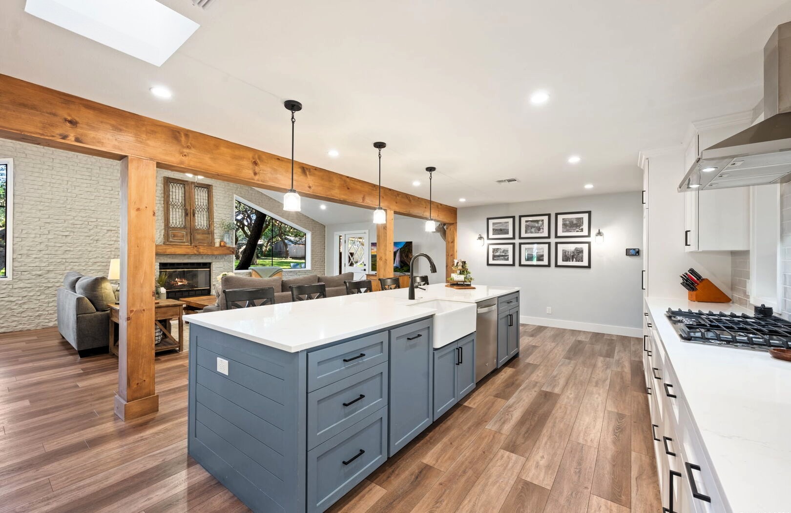 Open kitchen with blue-gray island, wood beams and living room beyond
