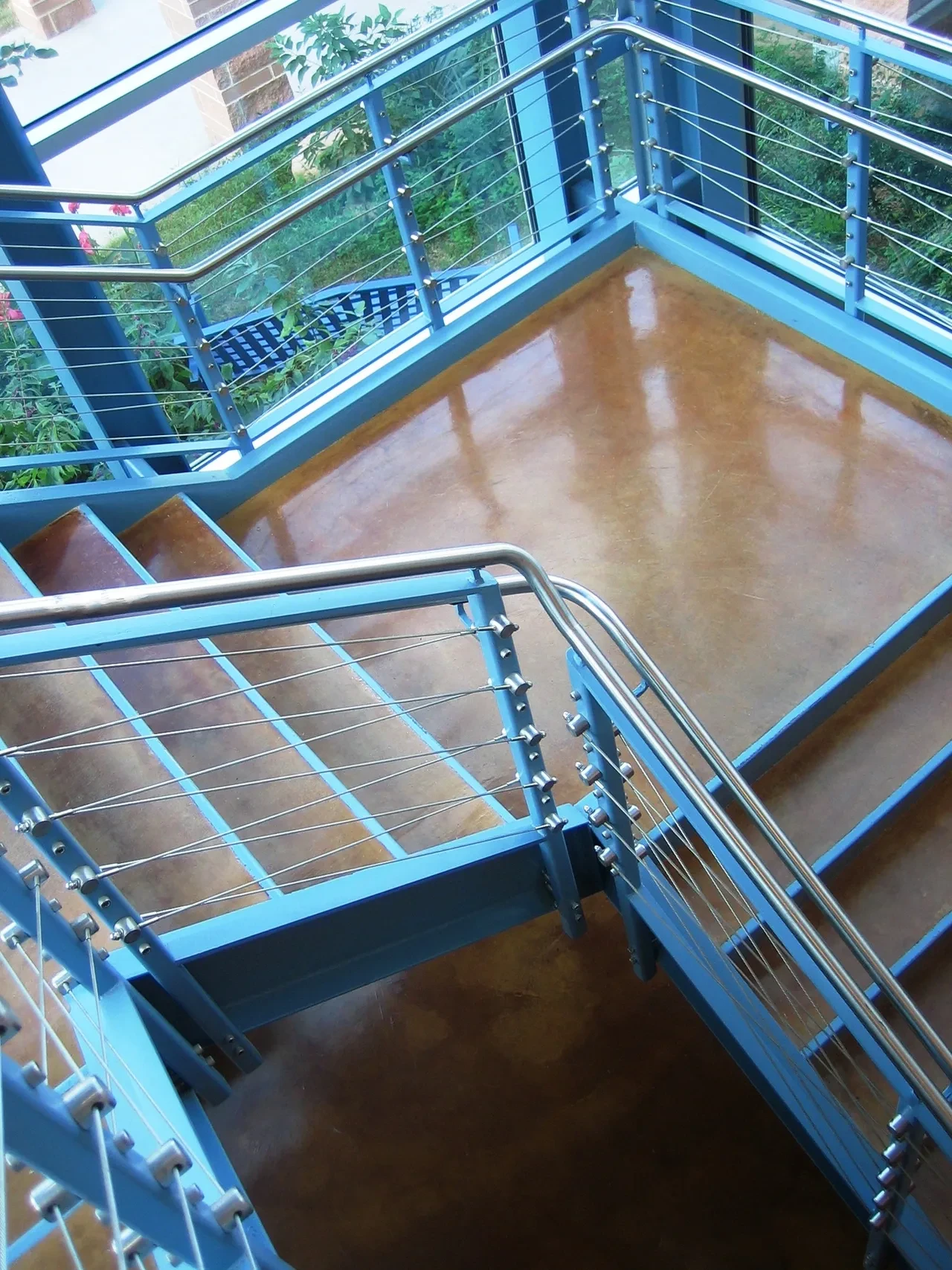 Blue steel staircase with cable railings and stained concrete