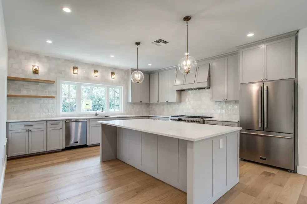 Modern kitchen with gray cabinetry, island and globe pendants